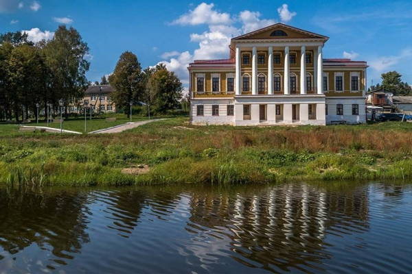 Старинное здание с колоннами на берегу водоема